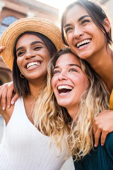 Langlopende reisverzekering Verschillende mensen zitten aan een tafel en lachen. Er staan laptops op tafel.